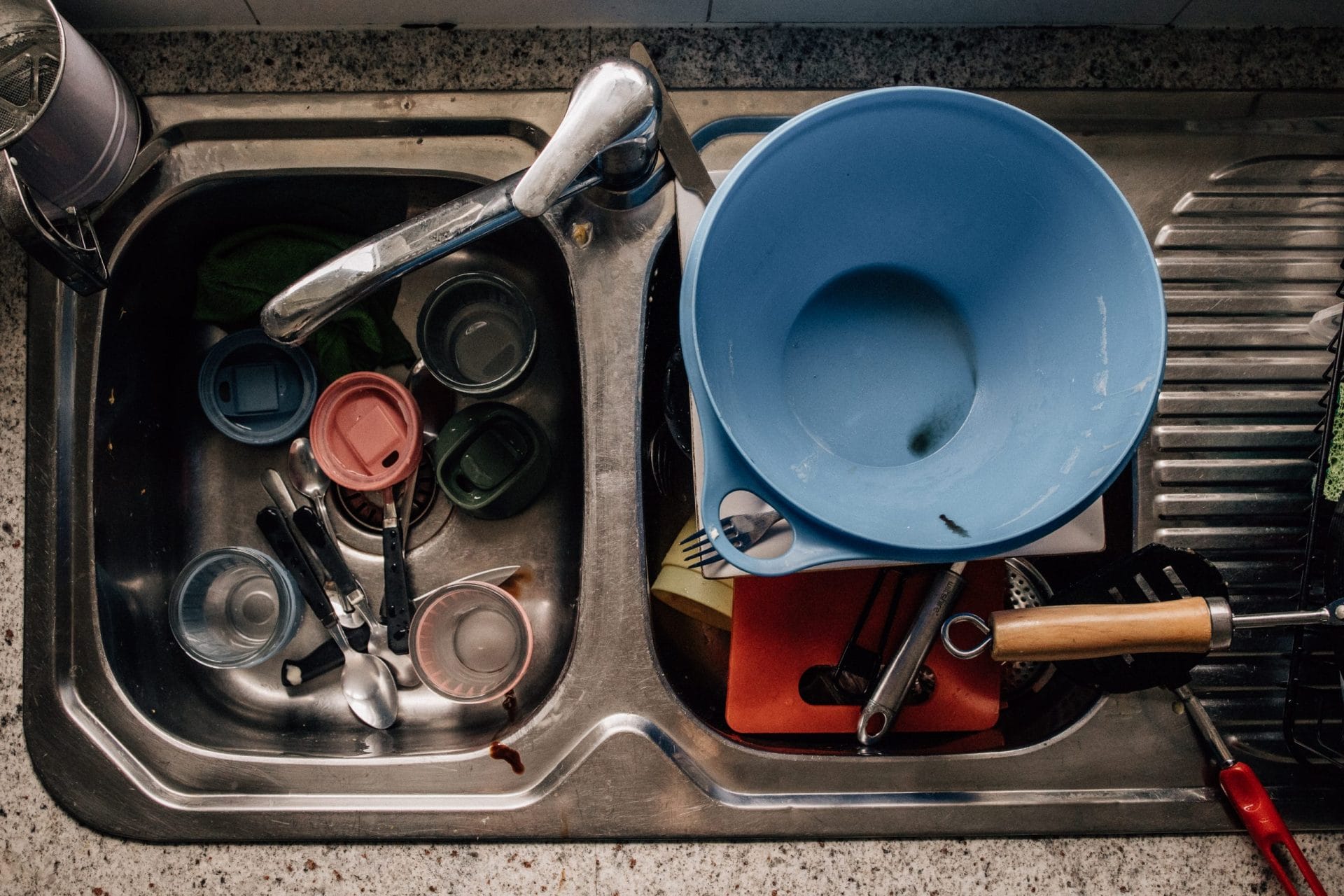 The need for perfection is stealing our joy 4 A stainless steel kitchen sink filled with various dirty dishes including pots, cups, and utensils.