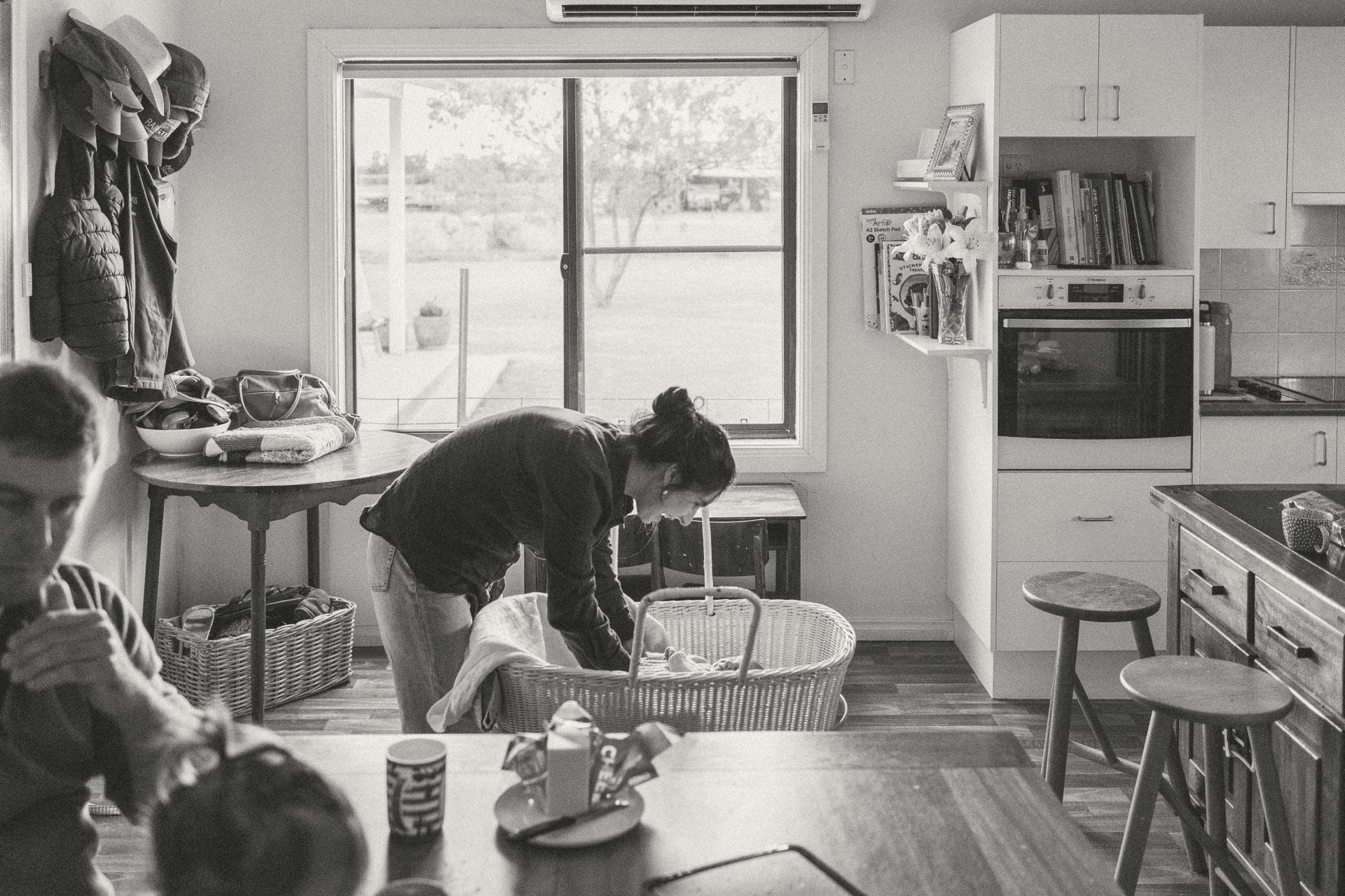 A black and white photo of a domestic scene in a kitchen, with a woman lighting candles on a cake as a child watches eagerly.